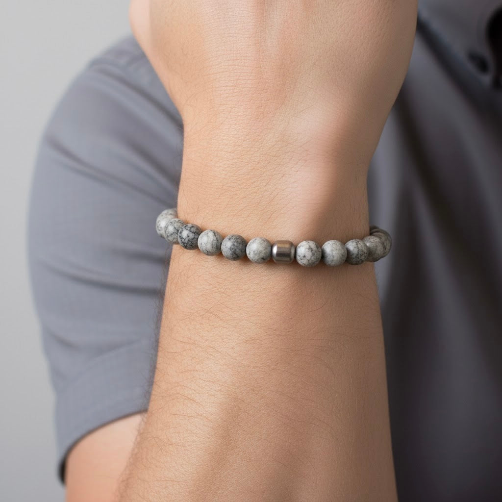 Gray map stone beaded bracelet on a men's wrist with a neutral background