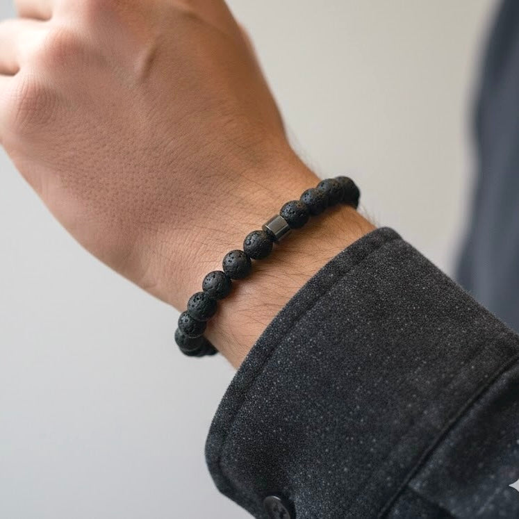Black lava rock bracelet on a wrist with a neutral background