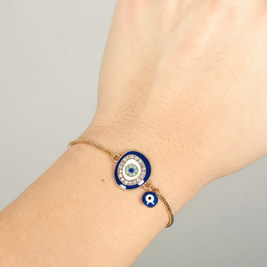 Bracelet with blue evil eye design and crystal accents on a wrist against a gray background