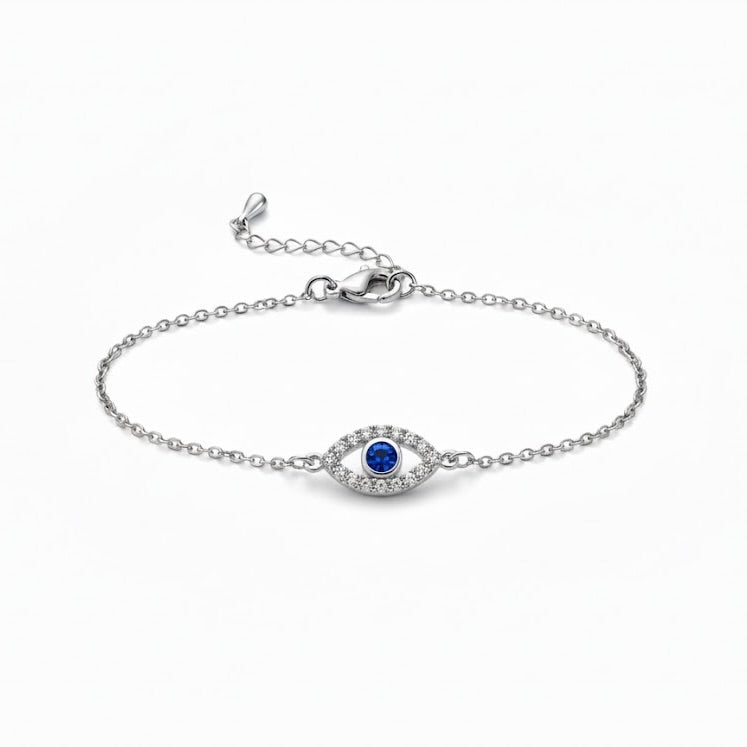 Silver bracelet with an eye shaped charm with crystals and a blue gemstone centerpiece on a white background