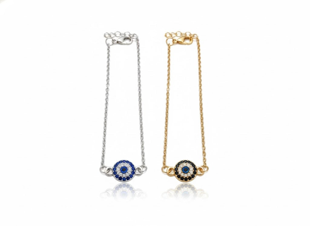 One gold and one silver chain anklet with a round eye charm with crystals on a white background