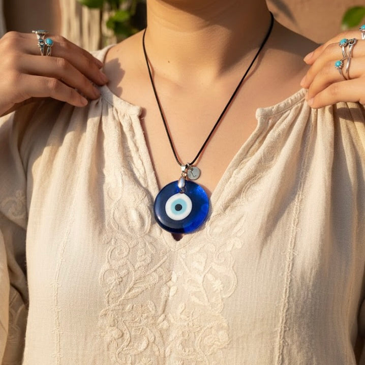 Person wearing a  40mm oversized evil eye medallion necklace with a boho beige top