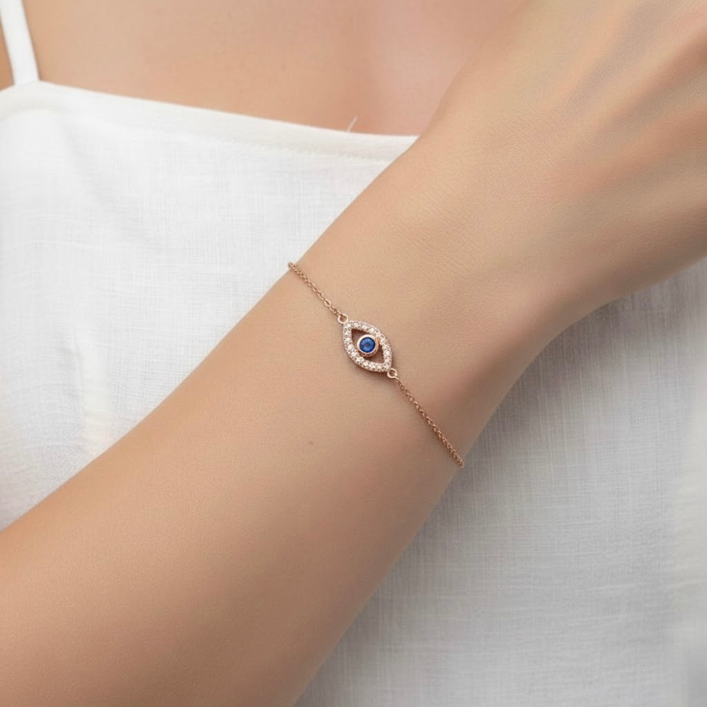 Rose gold eye bracelet with a blue gemstone on a wrist against a white background