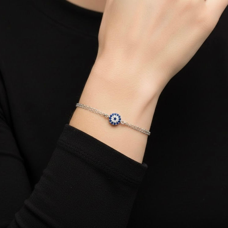 Bracelet with a round blue and white eye design on a wrist against a black background