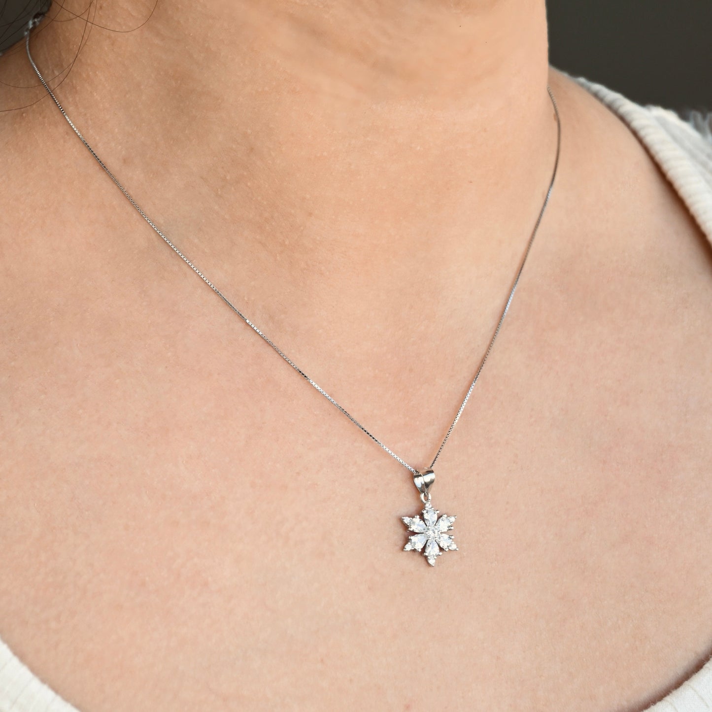 Silver necklace with a snowflake pendant on a person's neck