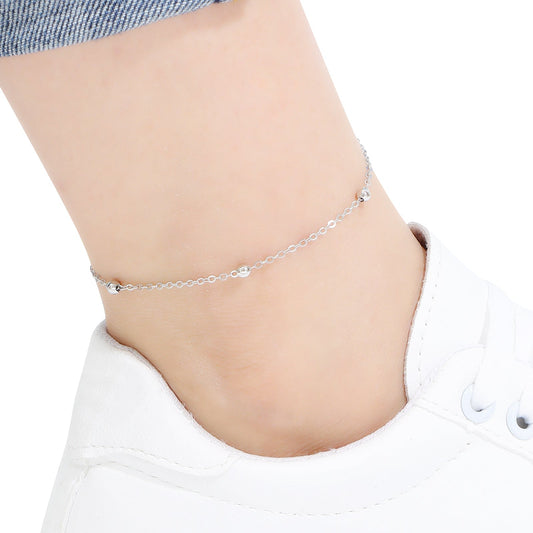 Silver beaded chain anklet on a person's ankle against a white background