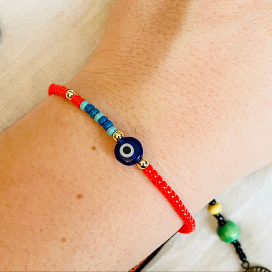 Colorful beaded bracelet with an eye charm on a wrist against a neutral background