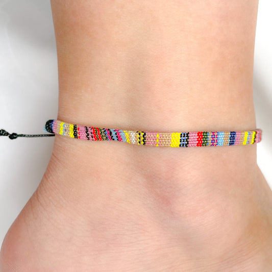 Multicolored woven surfer anklet on a person's ankle against a white background