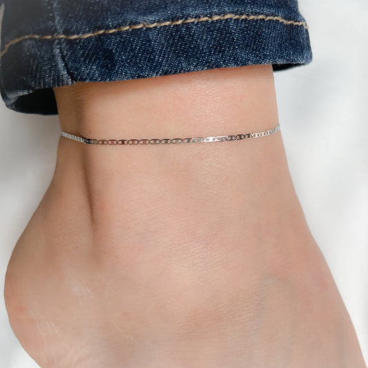 Delicate silver chain anklet on a person's ankle with a blurred background